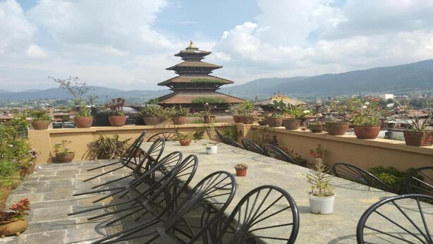 A tiered pagoda-style building with a view of a cityscape and mountains in the background. - MeroStay 155 GGH (Bhaktapur)