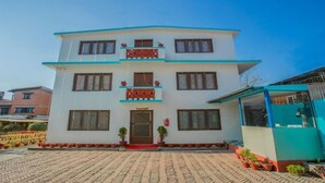 A two-story building with a flat roof, a central entrance, and a balcony with red railings. - MeroStay 154 White & Peace (Lalitpur)