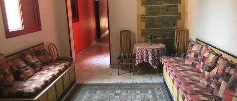 Un saló acollidor amb un sofà, una taula petita amb un mantell estampat i una catifa decorativa.