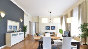 Ein modernes Wohnzimmer mit Essbereich, ausgestattet mit einer Sofagarnitur, einem Esstisch mit Stühlen und einem Fernseher.