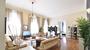 Ein modernes Wohnzimmer mit Sofa, Couchtisch und Fernseher. Es gibt eine Essecke mit Stühlen und einem Tisch.
