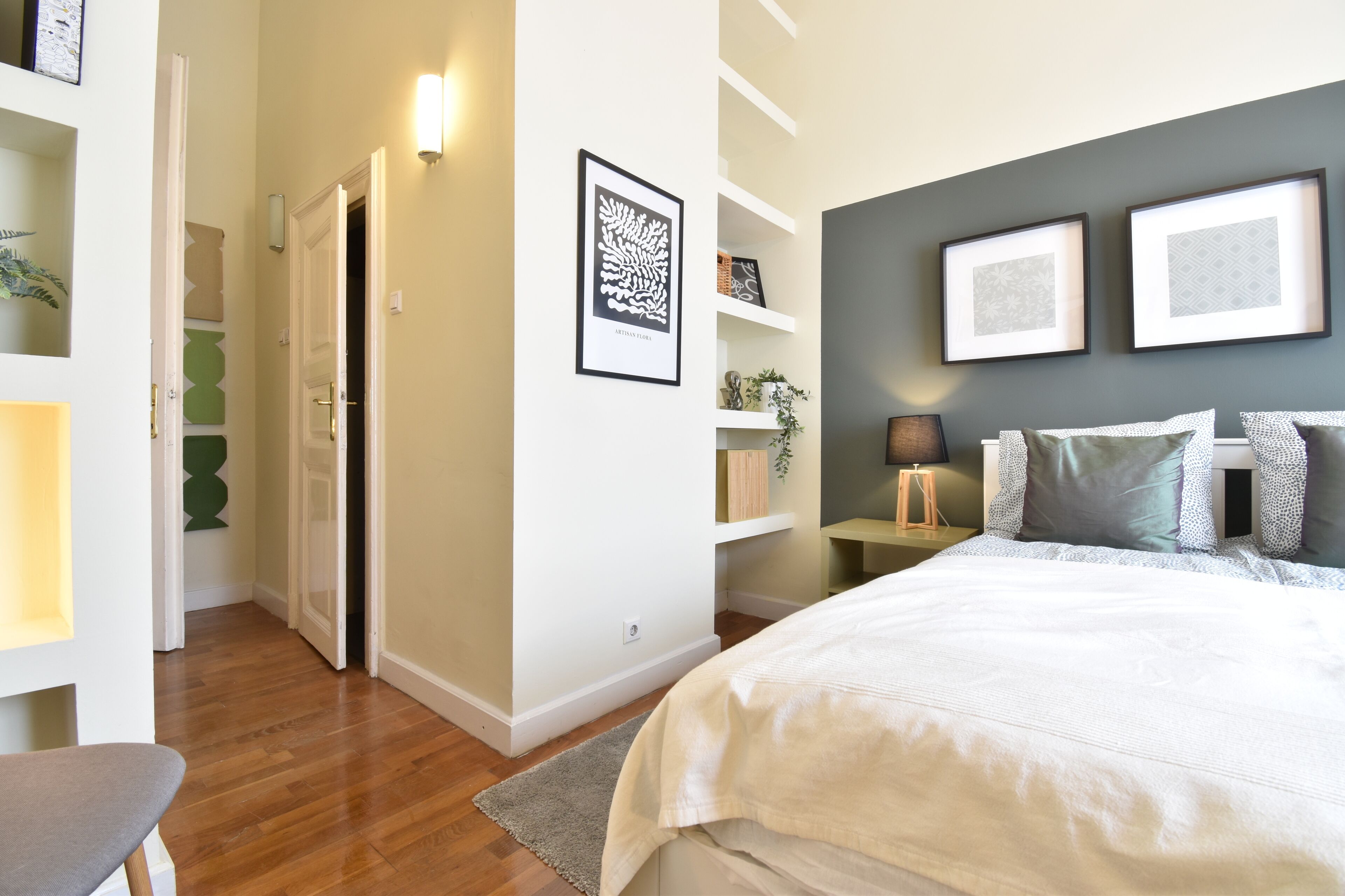 A bedroom with a bed, bedside tables, and wall-mounted shelves.