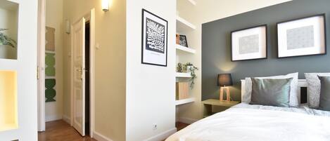 A bedroom with a bed, bedside tables, and wall-mounted shelves.