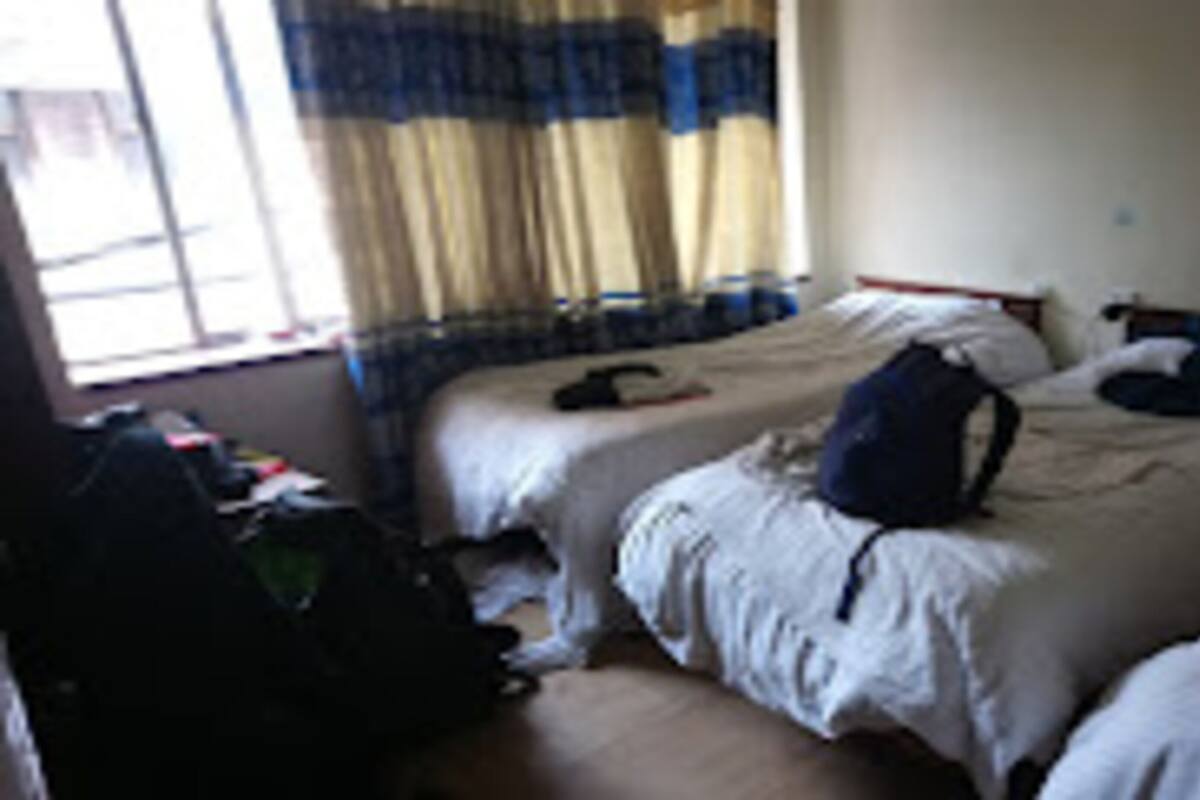A room with two beds, a window with curtains, and a visible bedspread.