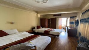 A hotel room with two beds, a wooden floor, a ceiling with a decorative light fixture, and a view of the outside through a door. - MeroStay 153 TH (Kathmandu)