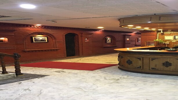 A lobby with a marble floor, wooden reception desk, and brick walls. - MeroStay 153 TH (Kathmandu)