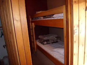 A bunk bed with a wooden frame and white bedding.