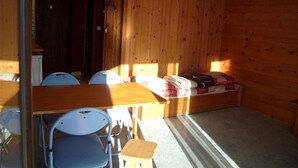 A small, cozy room with a wooden wall, a wooden table, and two chairs. - Studio cabin for 4 with parking in Crest-Voland (Crest-Voland)