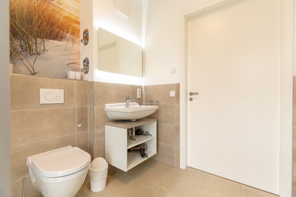 Ein modernes Badezimmer mit Toilette, Waschbecken und Spiegel.