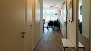 A hallway with a dining area, a bench, and a large mirror on the right. - Weiße Villen Wohnung 04 (Ostseebad Boltenhagen)