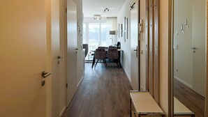 A hotel corridor with a wooden bench, a dining area with chairs and a table, and a large mirror on the right. - Weiße Villen Wohnung 07 (Ostseebad Boltenhagen)