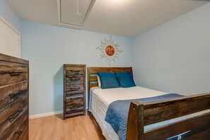 Quarto com cama de madeira, penteadeira e um armário alto.