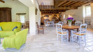 Un intérieur rustique avec un canapé vert, une table à manger en bois et des chaises.