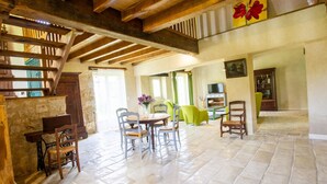 Un vaste salon doté d’un haut plafond, d’un coin repas et d’un escalier.