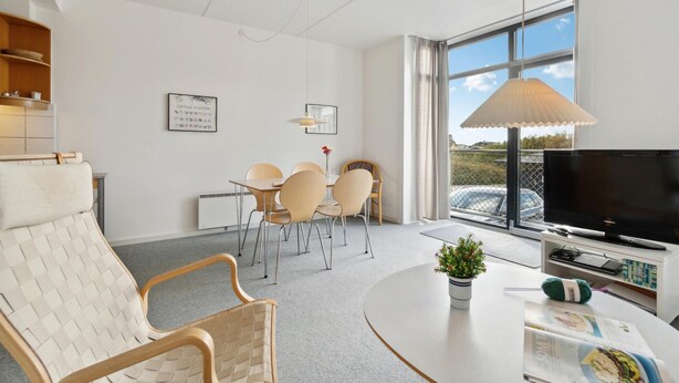Een moderne woonkamer met een eethoek, een televisie en een groot raam met uitzicht.