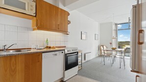 Een moderne keuken met houten kasten, een vaatwasser, een oven en een eethoek met een tafel en stoelen.