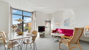 Een moderne woonkamer met een eethoek, een flatscreen televisie en een helder uitzicht.