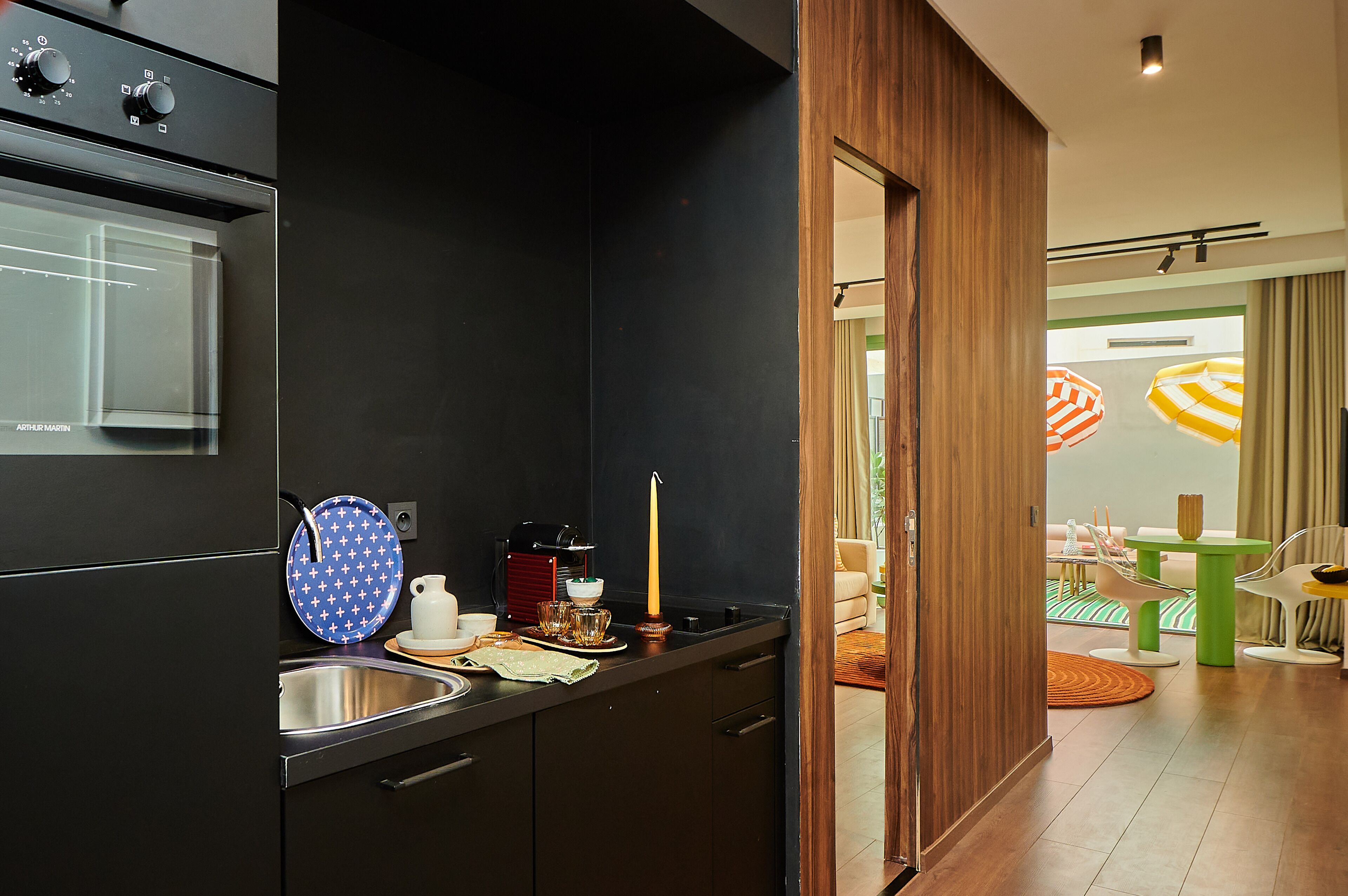 Una cocina moderna con horno empotrado, un lavamanos y una zona de comedor con mesa y sillas.