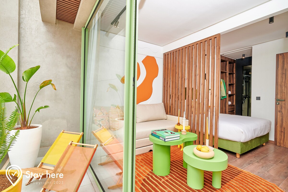 A modern bedroom with a bed, green furniture, a potted plant, and a sliding wooden screen.