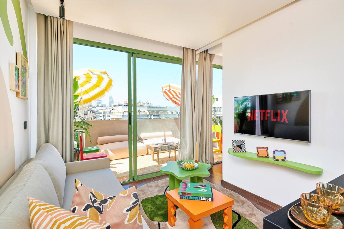 Una sala de estar moderna con un sofá, una mesa de centro, un televisor y un balcón con vistas a la ciudad.