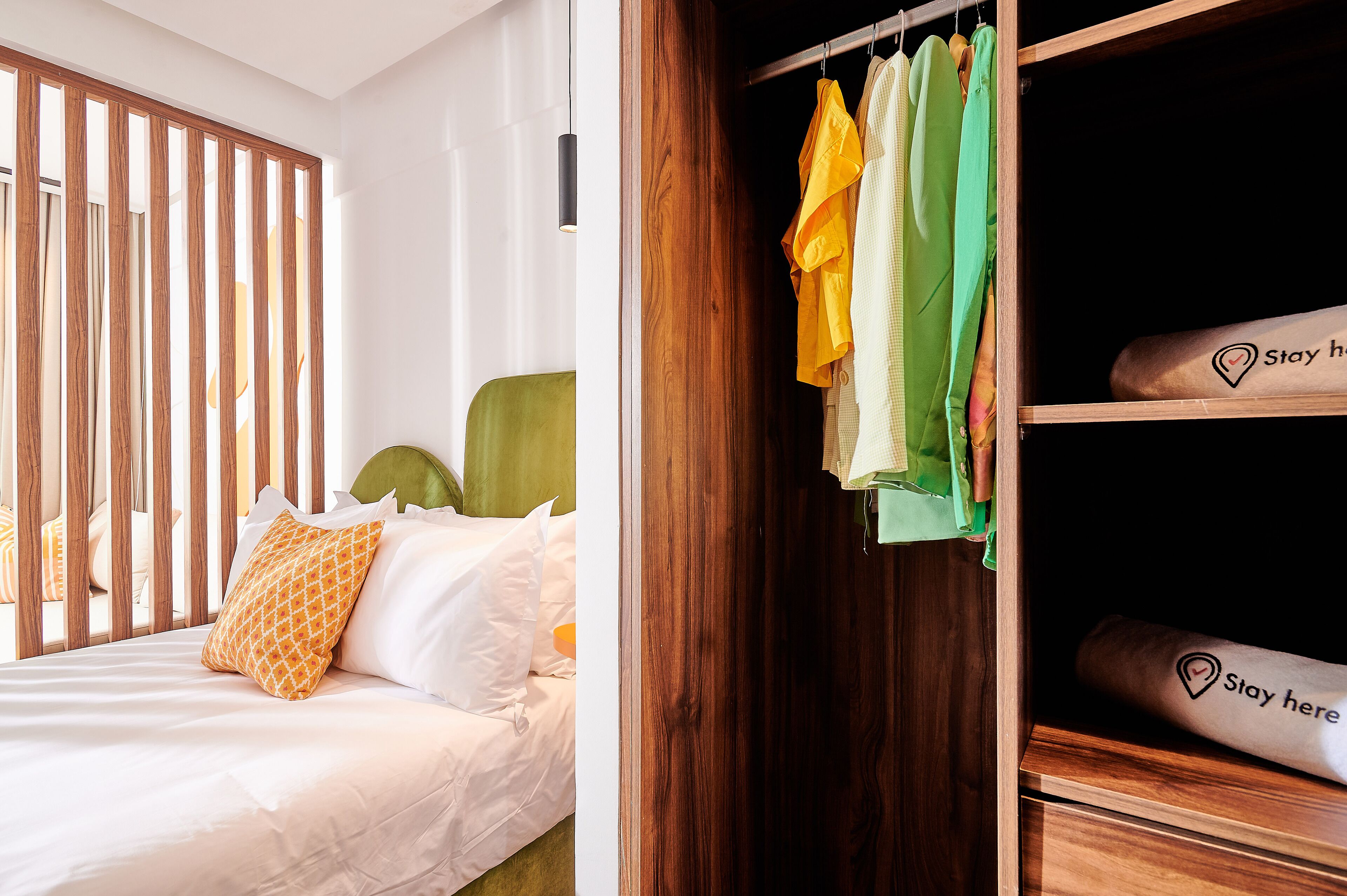 A bedroom with a bed, a wooden wardrobe, and a 'Stay here' sign on the wardrobe.