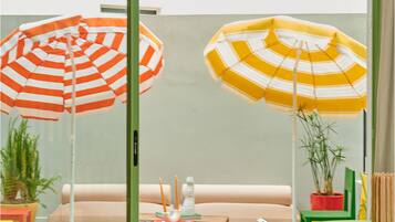 A modern interior with a green-striped floor, a seating area with a table, and two large striped umbrellas.