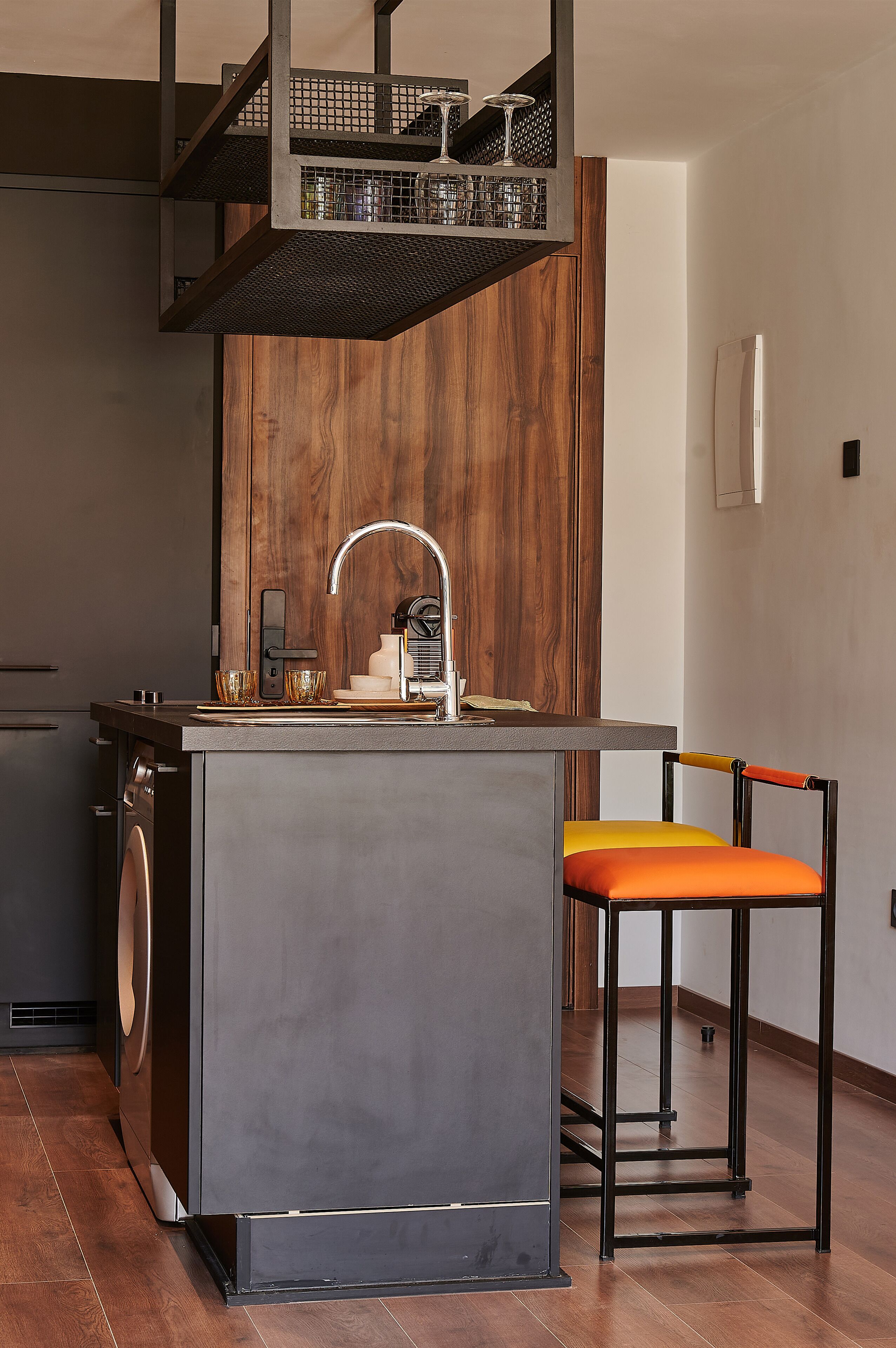 A modern kitchen with a wooden accent wall, a built-in sink, and a bar area with a stool.