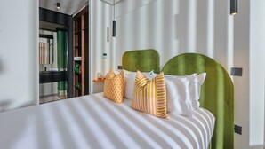 Una cama bien hecha con ropa de cama a rayas y un cabecero tapizado en verde.