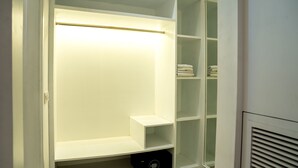 A walk-in closet with open shelving, a hanging rod, and a built-in heater. - Redwood Resort (Panchkula)