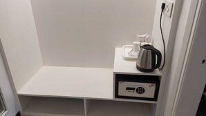 A small, white, enclosed space with a shelf holding a kettle, a cup, and a tray. - Redwood Resort (Panchkula)