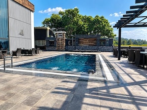 A rectangular swimming pool with a tiled edge, surrounded by outdoor seating and a pergola. - Redwood Resort (Panchkula)