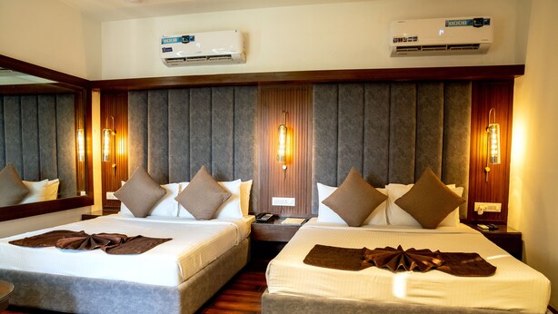 A hotel room with two beds, a wooden floor, and a wall-mounted air conditioner. - Redwood Resort (Panchkula)