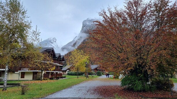 A residential area with houses, a pathway, and a mountain in the background. - Bel Appartement Avec Piscine - Le Grand Tétras (Samoëns)