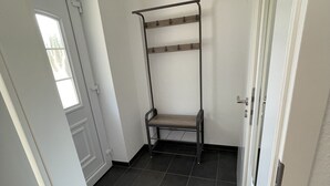 A room with a door, a window, a metal rack with shelves, and dark tiled flooring. - Büschem feel-good paradise (Lindlar)