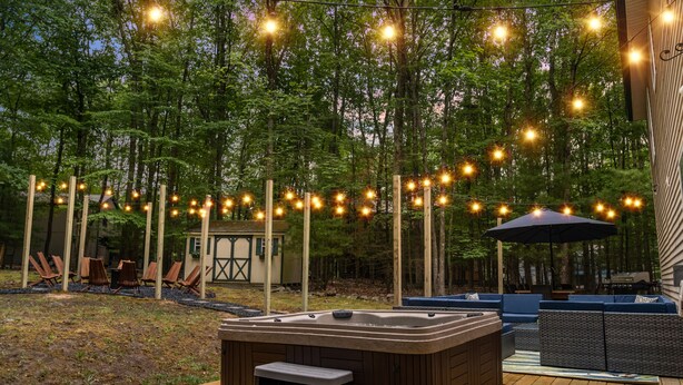 Eine Terrasse im Freien mit Whirlpool, Sitzgelegenheit und Lichterkette.