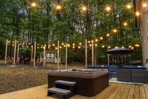 Une terrasse extérieure dotée d’un jacuzzi, d’un espace salon et de guirlandes lumineuses.
