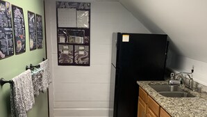 Eine kleine Küche mit Kühlschrank, Spüle und Holzschränken.