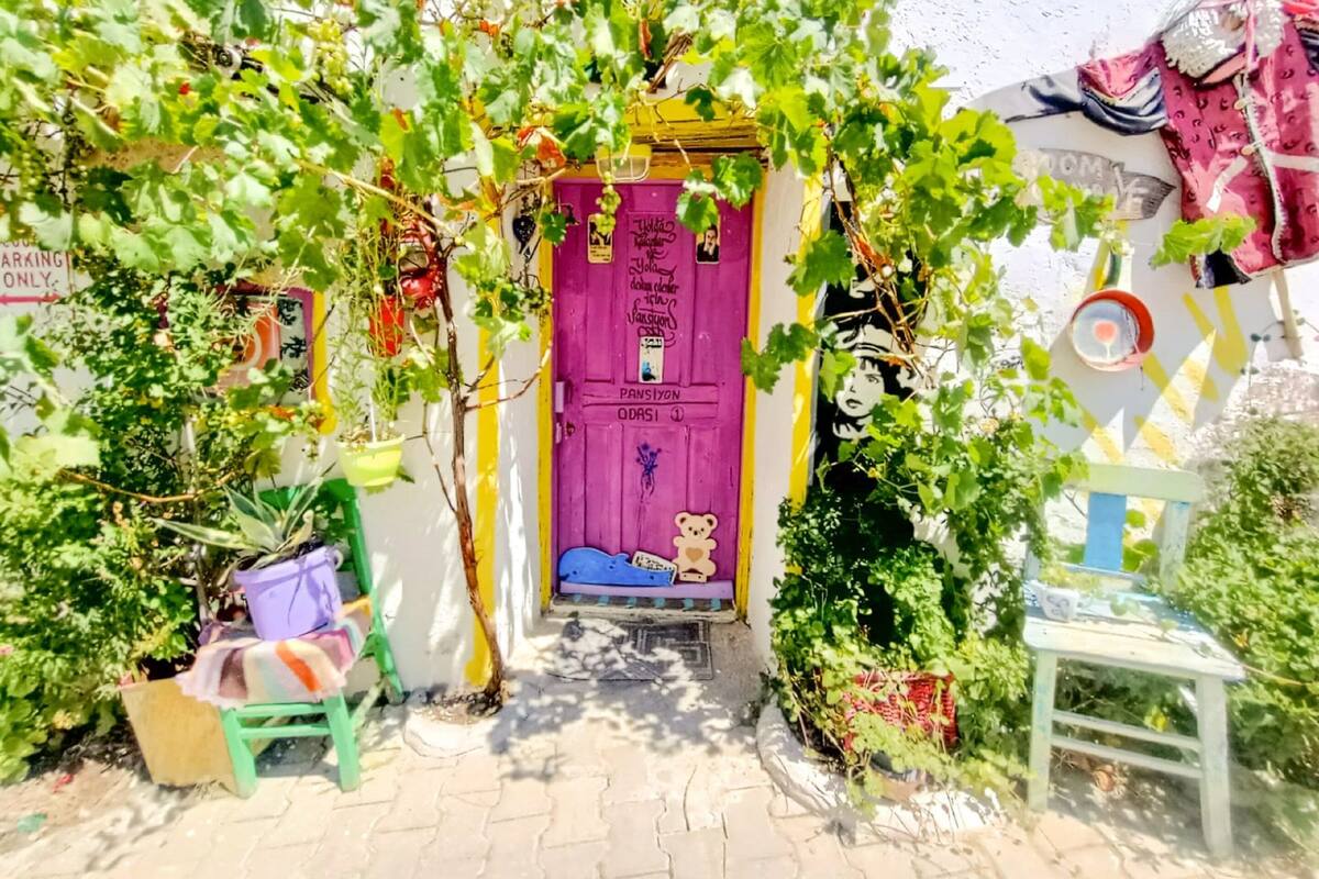 A colorful entrance with a purple door, a small bench, and a chair outside.