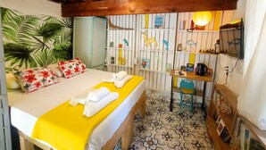 A room with a bed, a desk, a chair, a bookshelf, and a wall with a tropical leaf mural. - Mell10 House (Urla)