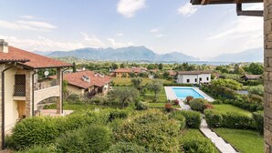 A residential area with a swimming pool, stone buildings, and a mountainous backdrop. - Lago Blu with pool and lake view (Manerba del Garda)