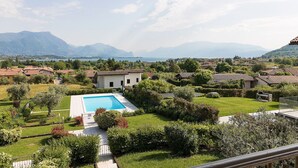 A residential area with a swimming pool, surrounded by lush greenery and mountains in the background. - Lago Blu with pool and lake view (Manerba del Garda)