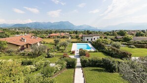 A residential area with a swimming pool, surrounded by lush greenery and a clear view of distant mountains. - Lago Blu with pool and lake view (Manerba del Garda)