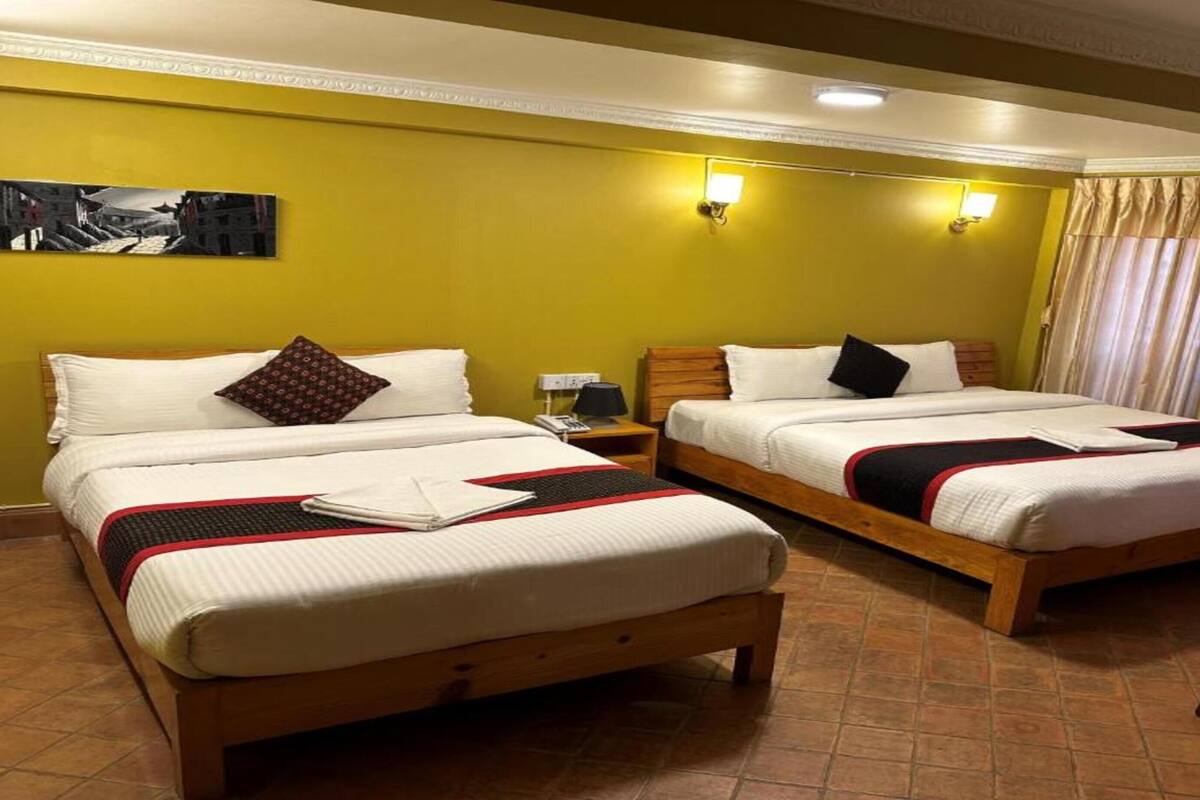 Una habitación de hotel con dos camas individuales, una mesita y una silla.