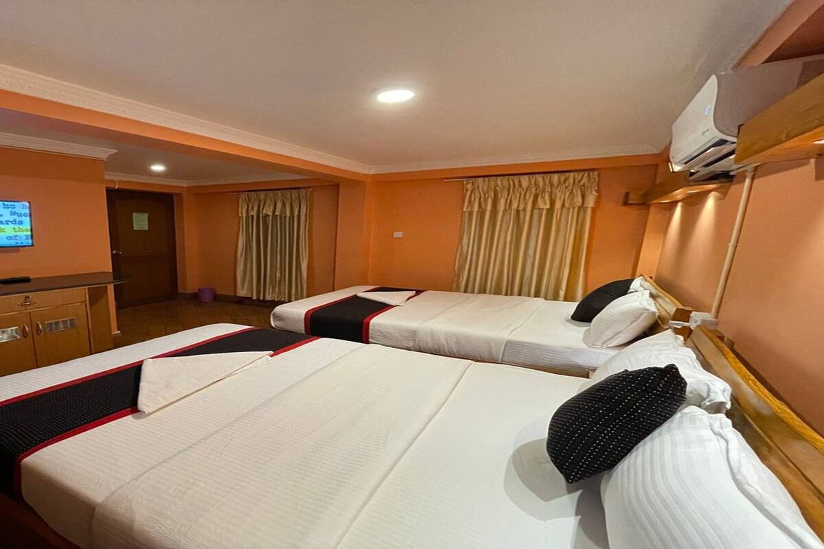 Habitación de hotel con dos camas, un escritorio, un televisor y aire acondicionado.