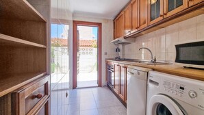 Una cuina compacta amb armaris de fusta, forn de microones integrat, rentadora i un rentaplat.