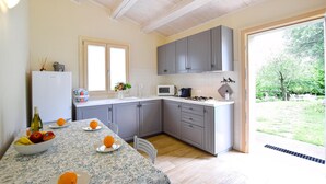 Una cocina moderna con armarios grises, una encimera blanca y una mesa de comedor con fruta.