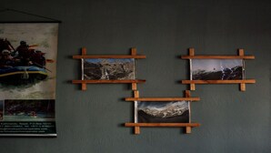 A wall with a poster of a rafting trip and three framed photographs of mountainous landscapes. - Merostay 158 Hotel RM (Kathmandu)