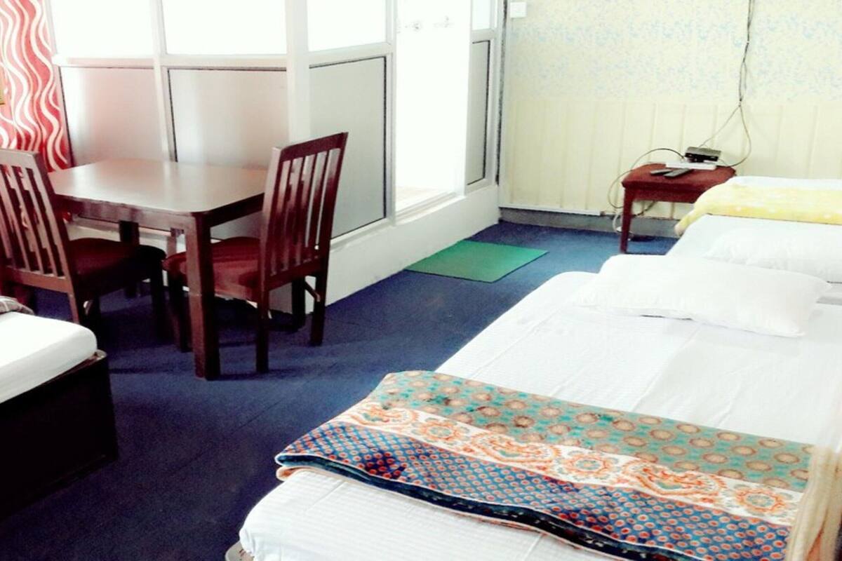 A hotel room with a bed, a desk, two chairs, and a small table.