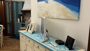 A kitchen with a blue and white tiled countertop, a painting of a beach scene, and a cabinet with drawers. - Villa Crilu Sardinia, cozy, with sea view, swimming pool and private parking space (Tanaunella)