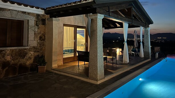A covered outdoor area with a pool, stone walls, and a view of the mountains at dusk. - Villa Crilu Sardinia, cozy, with sea view, swimming pool and private parking space (Tanaunella)